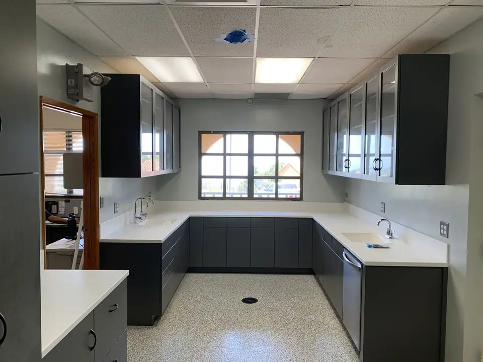 Charcoal custom cabinets with frosted glass-front uppers and white countertops, built by Ogden Woodworking, a custom cabinets maker in Goleta, CA