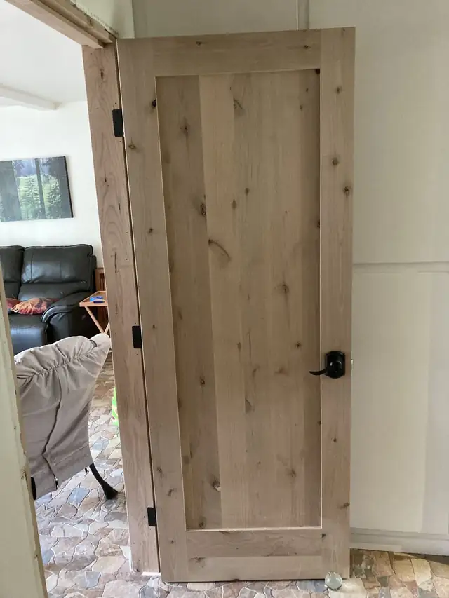 Custom knotty wood plank interior door with a black lever handle and black hinges