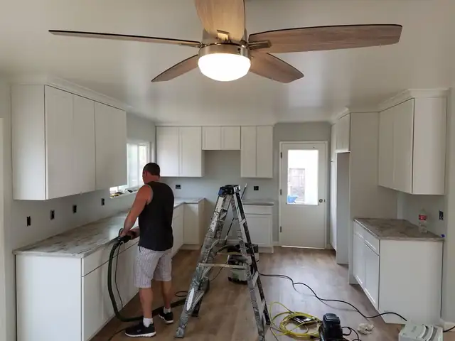 White shaker kitchen cabinets with crown molding while the new countertops are being finished